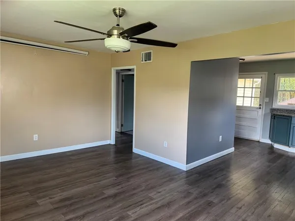 a view of an empty room with wooden floor and a window