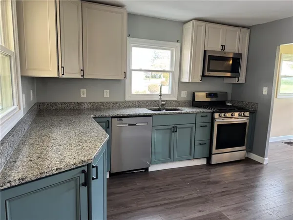 a kitchen with stainless steel appliances granite countertop a stove a sink and a microwave