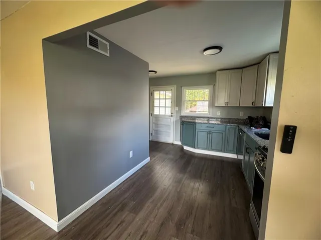 a kitchen with granite countertop a refrigerator a sink a stove and cabinets