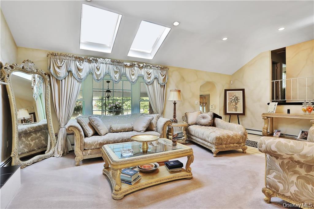2 Split Tree Drive New Windsor, NY 12553 - Photo 12 of 36 Carpeted living area with arched walkways, lofted ceiling, recessed lighting, a baseboard radiator, and a skylight
