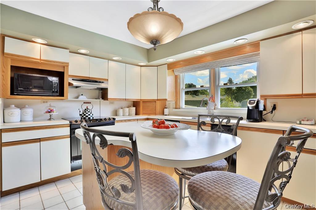 2 Split Tree Drive New Windsor, NY 12553 - Photo 20 of 36 Kitchen with black appliances, light countertops, white cabinets, hanging light fixtures, and a breakfast bar area