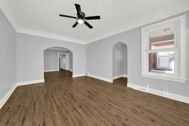 a view of empty room with wooden floor and fan