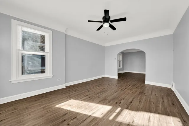 a view of empty room with wooden floor and ceiling fan