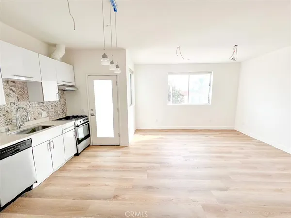 a large white kitchen with granite countertop a stove a sink and white cabinets