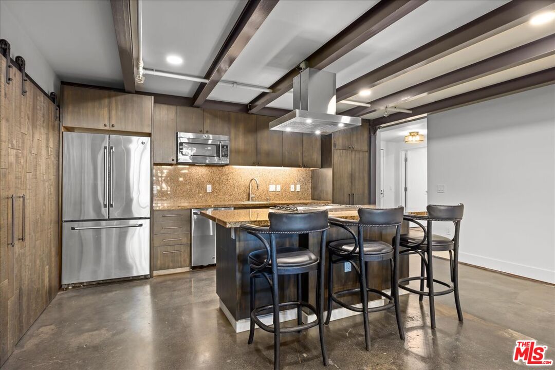 120 South Hewitt Street, Unit 6 Los Angeles, CA 90012 - Photo 13 of 48 a kitchen with stainless steel appliances granite countertop a table chairs and a refrigerator