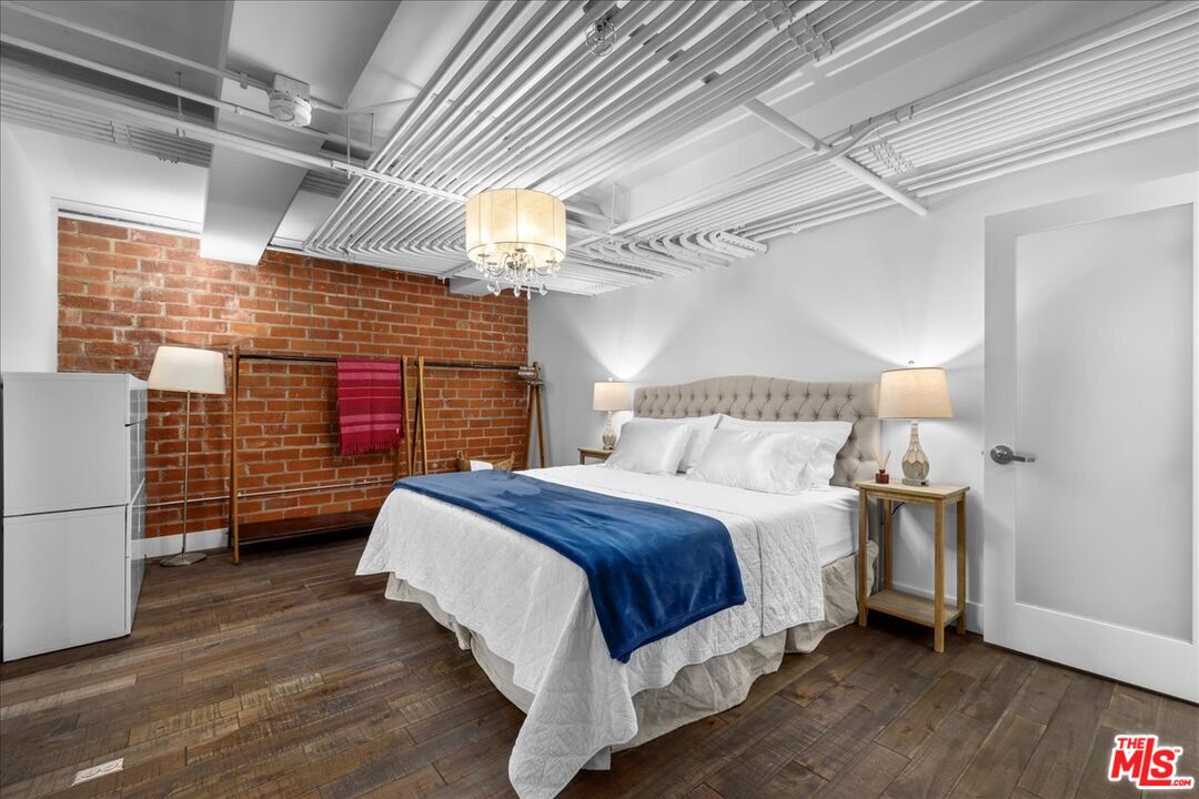 120 South Hewitt Street, Unit 6 Los Angeles, CA 90012 - Photo 26 of 48 a bedroom with a bed and a chandelier