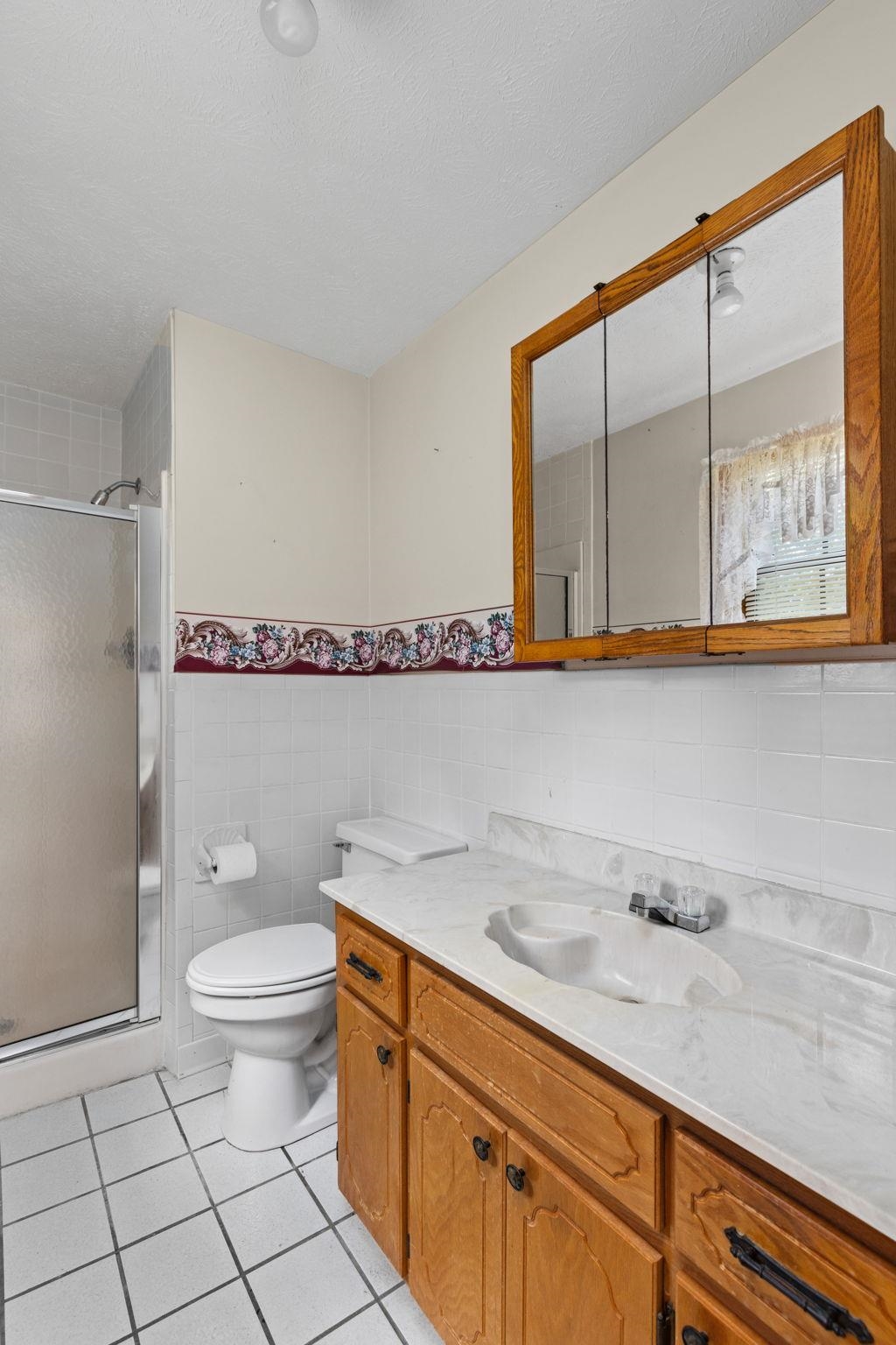 165 Highway 201 Reagan, TN 38368 - Photo 27 of 40 Bathroom featuring tile walls, vanity, light tile patterned floors, a stall shower, and a wainscoted wall