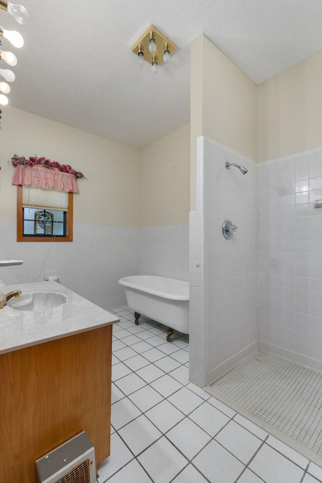 165 Highway 201 Reagan, TN 38368 - Photo 35 of 40 Full bathroom with light tile patterned floors, a walk in shower, vanity, a soaking tub, and tile walls