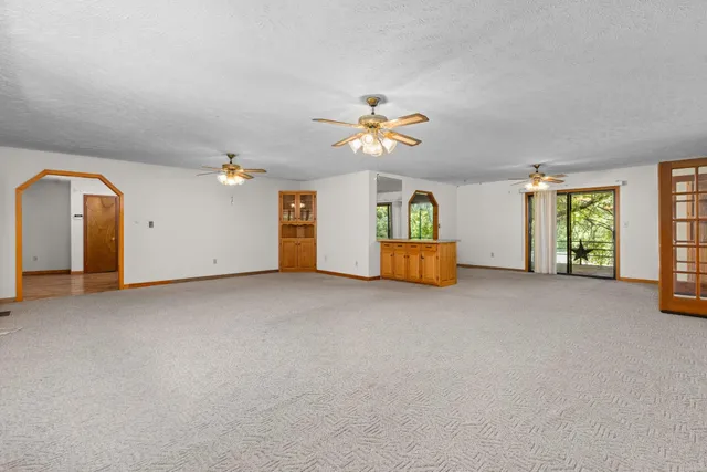 an empty room with windows and ceiling fan