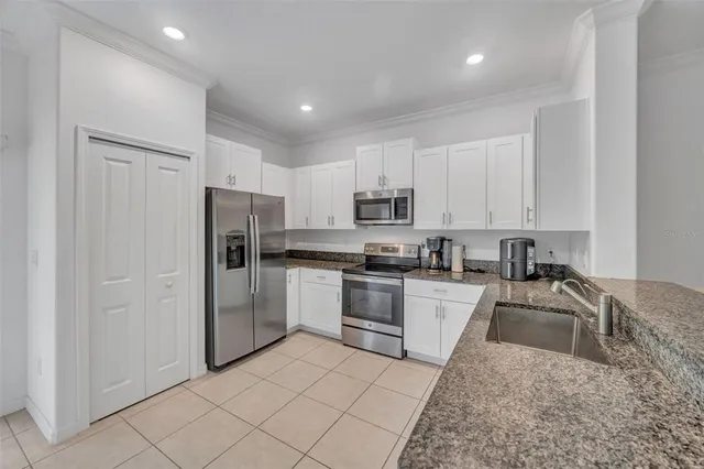 a kitchen with a sink a refrigerator and a stove top oven with white cabinets