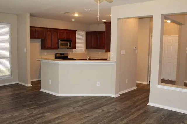 an empty room with wooden floor and windows