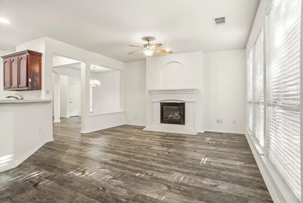 a view of an empty room with wooden floor fireplace and a window