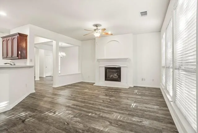 a view of an empty room with wooden floor fireplace and a window