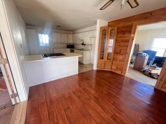 a living room with stainless steel appliances wooden floors and kitchen view