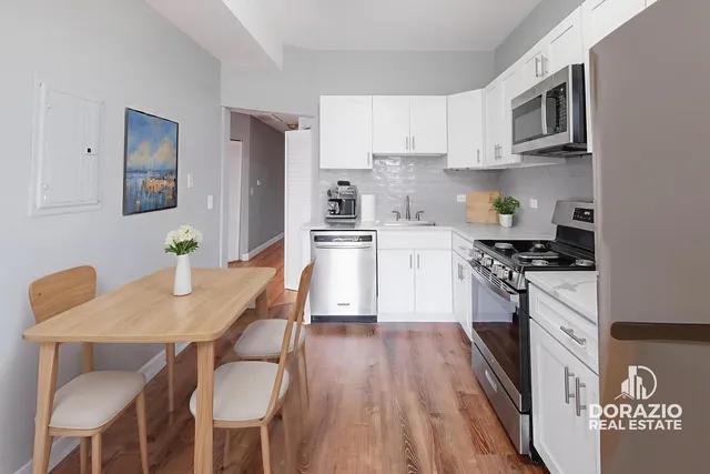 a kitchen with stainless steel appliances granite countertop a stove a sink dishwasher a microwave oven with a dining table and chairs with wooden floor