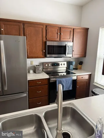 a kitchen with stainless steel appliances a sink a stove a microwave a refrigerator a counter and cabinets