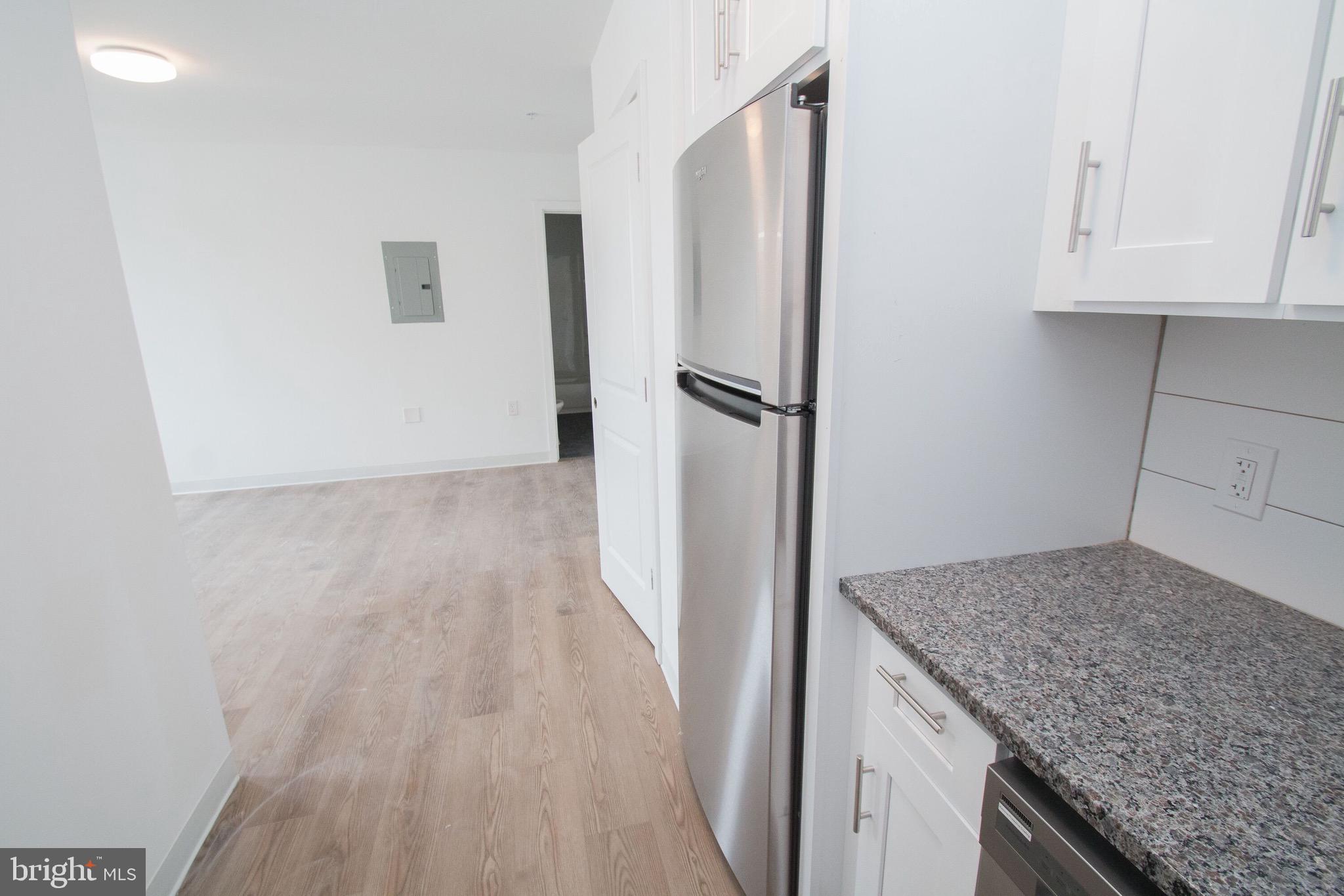a kitchen with granite countertop a refrigerator and a counter space