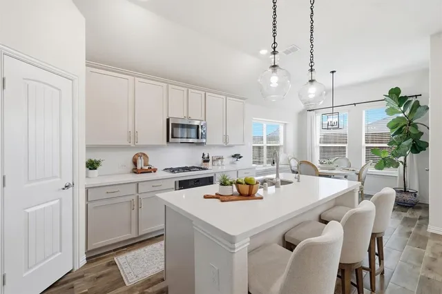 a kitchen that has a lot of white furniture and a wooden floor