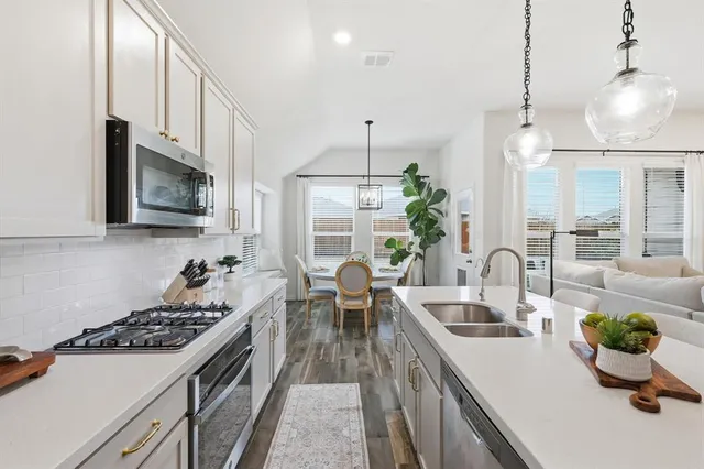 a kitchen with stainless steel appliances a dining table chairs and couches