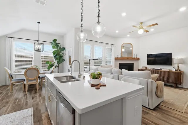 a kitchen with stainless steel appliances kitchen island granite countertop a dining table chairs and a refrigerator