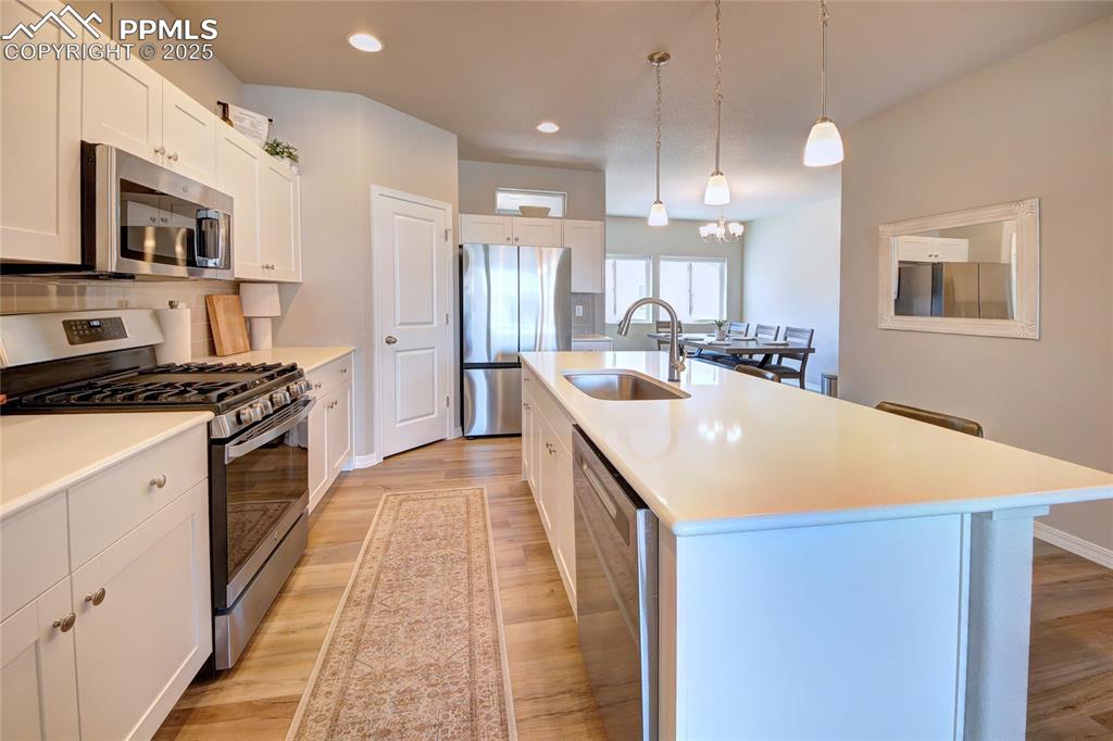 6069 Inman View Colorado Springs, CO 80924 - Photo 12 of 38 a kitchen with kitchen island a stove a sink a refrigerator and a microwave