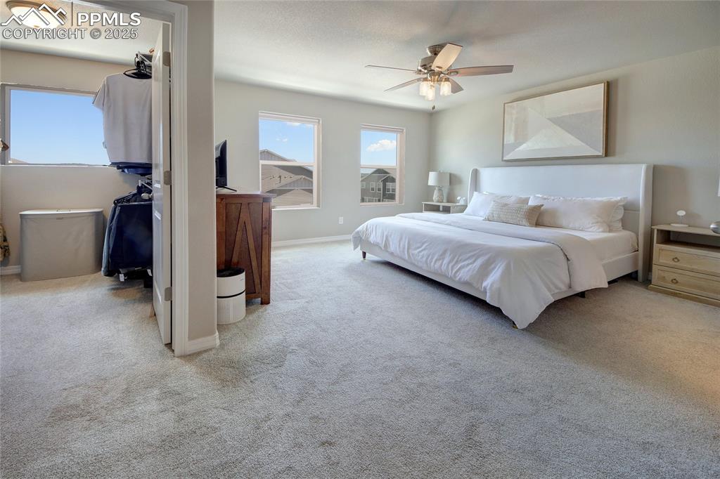 6069 Inman View Colorado Springs, CO 80924 - Photo 17 of 38 a spacious bedroom with a bed and a chandelier