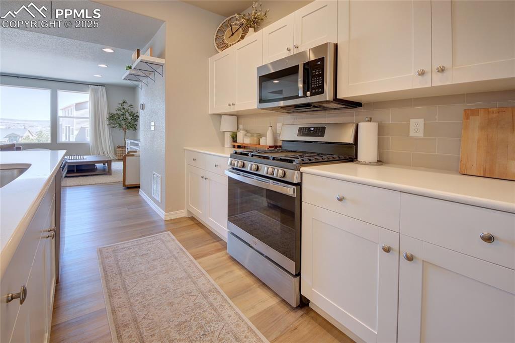 6069 Inman View Colorado Springs, CO 80924 - Photo 6 of 38 a kitchen with stainless steel appliances granite countertop a stove a sink dishwasher and a microwave oven with white cabinets