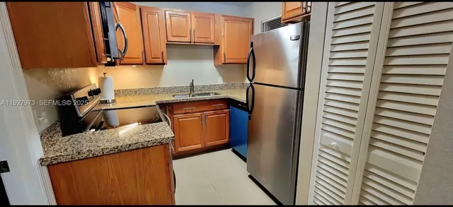 a kitchen with granite countertop a refrigerator and a sink
