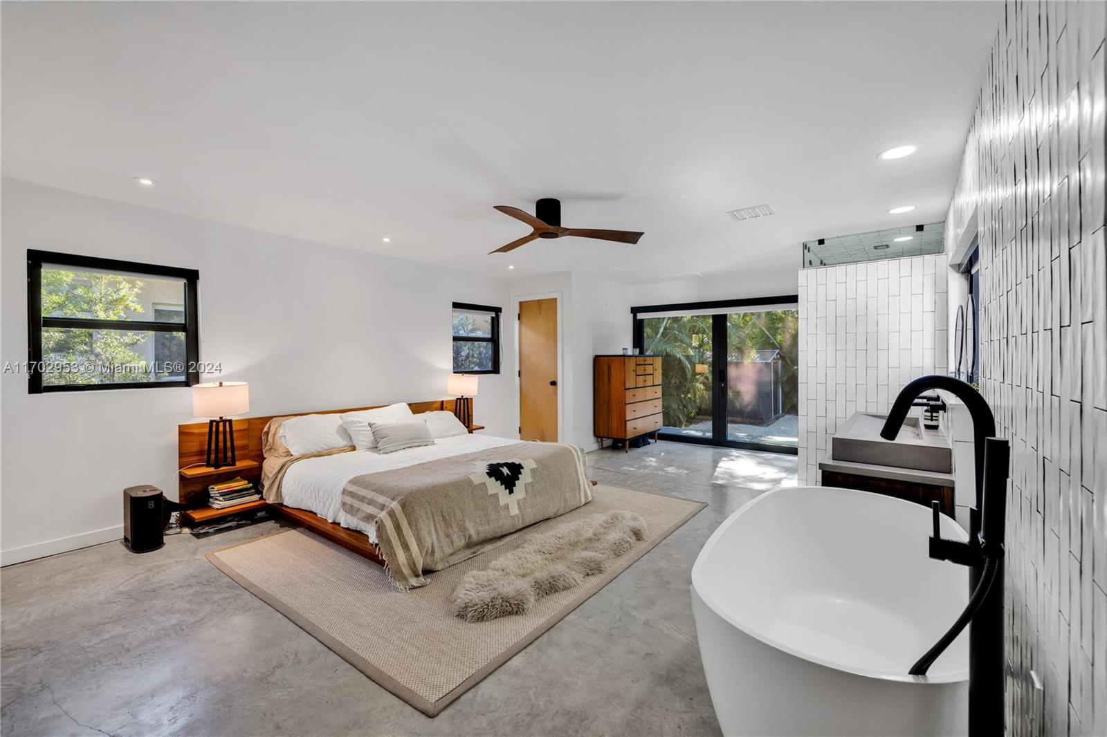 56 Northeast 46th Street Miami, FL 33137 - Photo 19 of 28 a spacious bedroom with a bed a couch and a window
