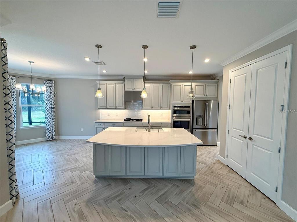 5967 Maidenstone Way Palmetto, FL 34221 - Photo 7 of 28 a large kitchen with kitchen island a stove a refrigerator a sink and a oven with wooden floor