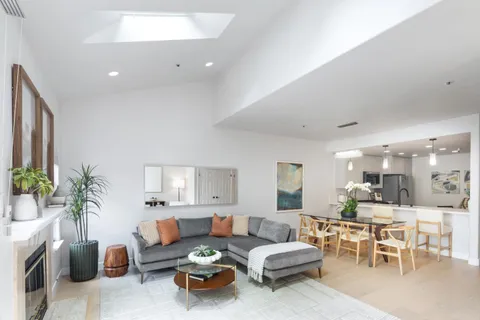 a living room with furniture kitchen and a potted plant