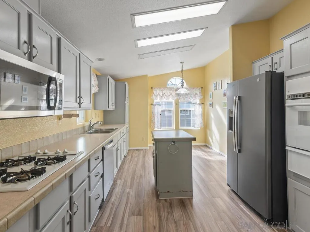 9500 Harritt Road, Unit 31 Lakeside, CA 92040 - Photo 6 of 33 a kitchen with stainless steel appliances granite countertop a refrigerator a sink dishwasher a stove and white countertops with wooden floor