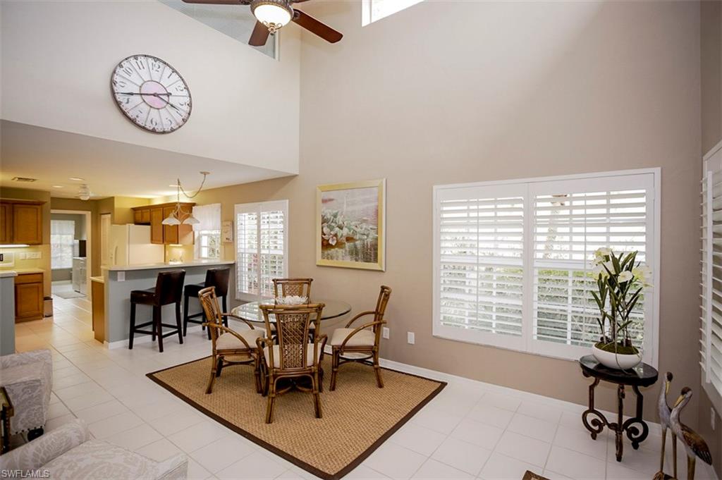 168 Napa Ridge Way Naples, FL 34119 - Photo 12 of 22 a view of a dining room and livingroom with furniture wooden floor and a large window