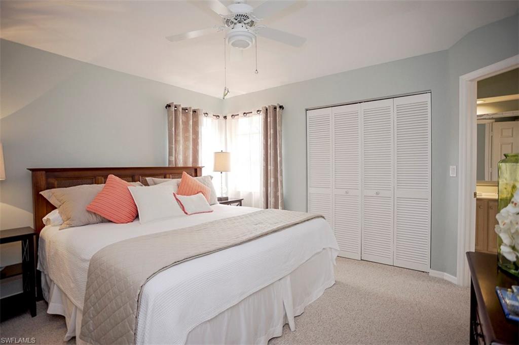 168 Napa Ridge Way Naples, FL 34119 - Photo 16 of 22 a bedroom with a bed and a chandelier