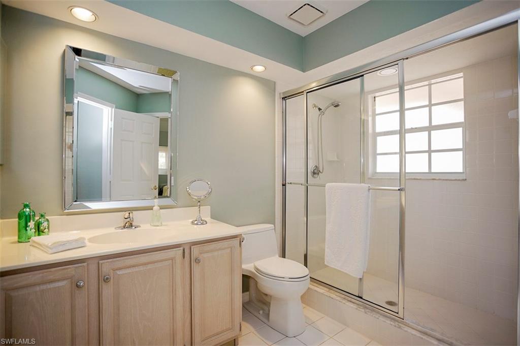 168 Napa Ridge Way Naples, FL 34119 - Photo 17 of 22 a bathroom with a toilet a sink a mirror and a shower