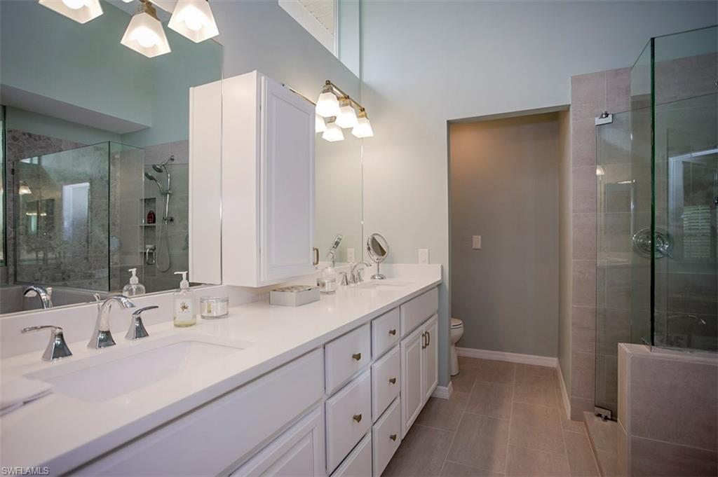 168 Napa Ridge Way Naples, FL 34119 - Photo 10 of 22 a bathroom with double vanity sink a large mirror a shower and a bathtub