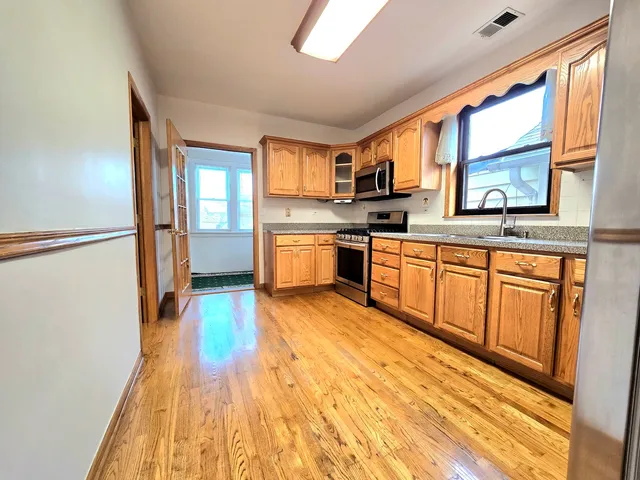 a large kitchen with cabinets wooden floor and stainless steel appliances