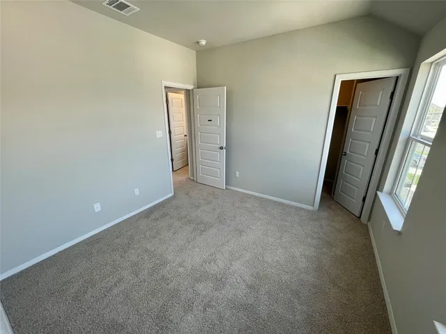 an empty room with mirror and a bathroom