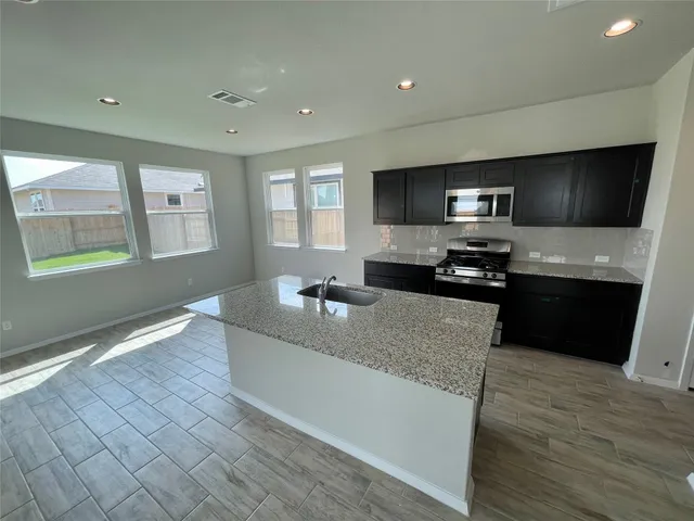a large kitchen with stainless steel appliances a large counter top a stove a microwave a sink and dishwasher