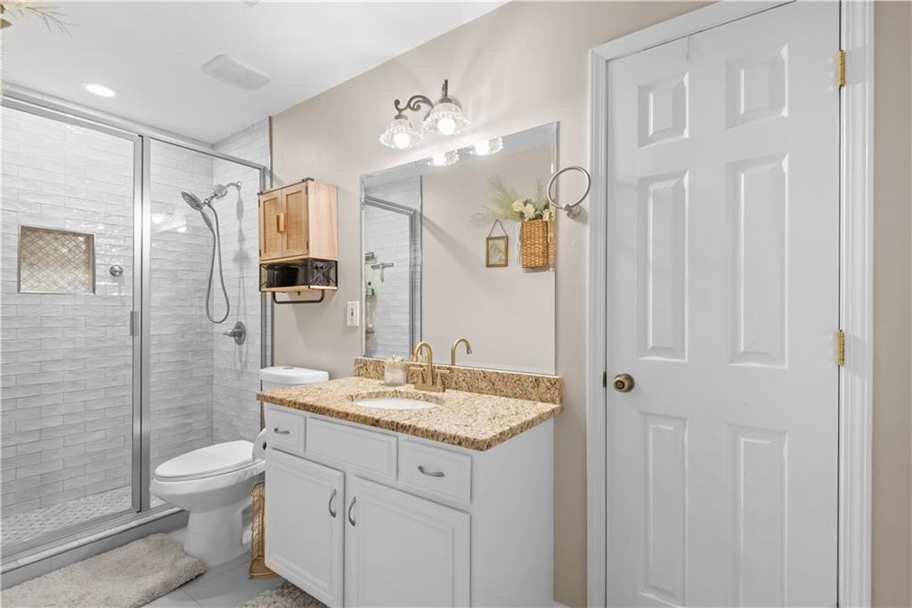 414 Parker Branch Road Barnesville, GA 30204 - Photo 49 of 101 a bathroom with a granite countertop sink a toilet a mirror and shower