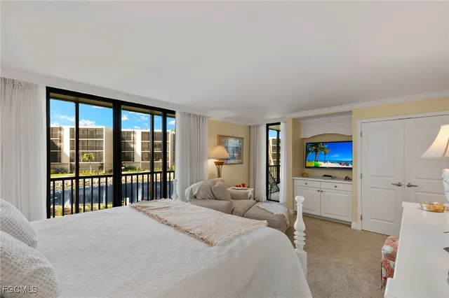 a bedroom with a large bed couch and two windows