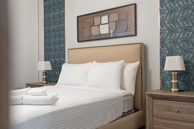 a bedroom with a large bed and a lamp on dresser