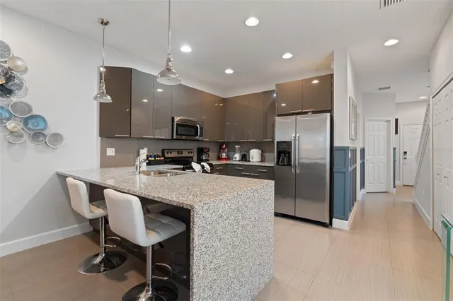 a kitchen with kitchen island a dining table chairs stainless steel appliances and cabinets