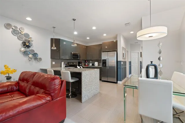 a kitchen with stainless steel appliances granite countertop a refrigerator a oven a sink a stove and a dining table with wooden floor