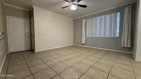 an empty room with chandelier fan and windows