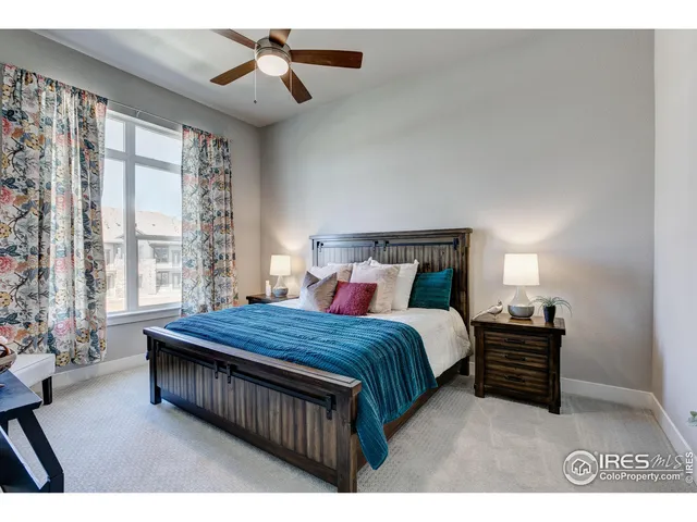 a bedroom with a bed couch chandelier and a window