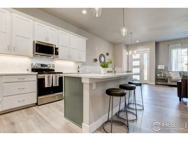 a kitchen with a stove a refrigerator and a dining table with wooden floor