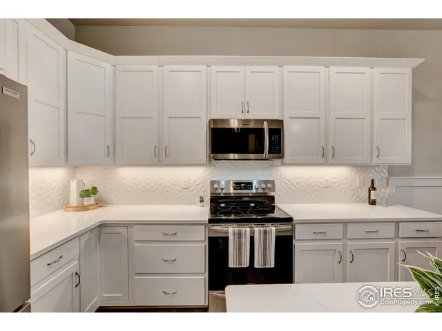 a kitchen with white cabinets and appliances