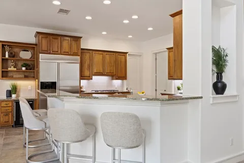 a kitchen with kitchen island granite countertop wooden cabinets and a refrigerator