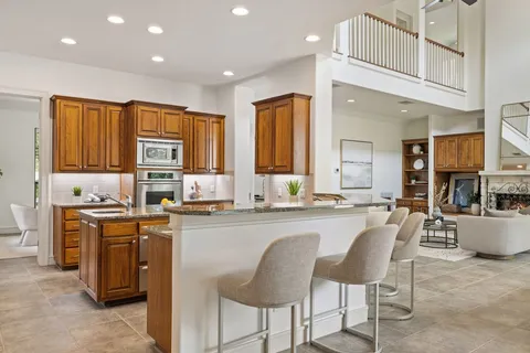 a kitchen with stainless steel appliances granite countertop a stove top oven a sink a dining table and chairs